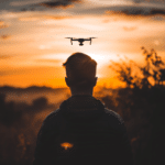 Homme qui pilote un drone face au soleil