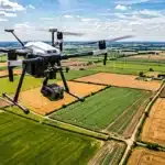Drone professionnel avec caméra survolant patchwork de champs agricoles