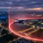 Drone volant au-dessus d'une ville nocturne avec traînées lumineuses rouges
