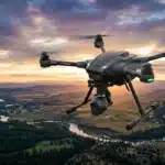 Drone noir en vol au-dessus vallée avec rivière et montagnes