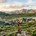 Deux randonneurs en montagne avec vue panoramique sur vallée verdoyante